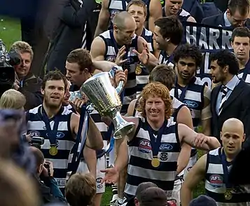 A group of players walk holding a silver trophy