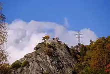 A rocky mound with castle ruins. To the right of the ruin is an electric pylon.