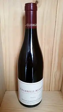 A bottle of Domaine Christian Clerget Chambolle-Musigny wine. It is dark red with a white label.