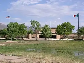 Short building with Mexican and American flags flying