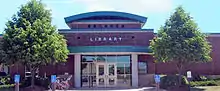 A single-story brick library with a tall front entrance on a clear summer day, pictured 2013