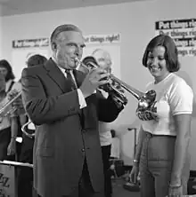 63-year-old man in suit playing a trumpet