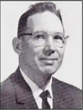 an old newspaper looking headshot of a white man in glasses in 3/4 profile