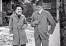 Screenshot of Charlie Chaplin (left) in scene with Henry Lehrman in "Making A Living"