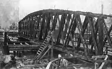 Black and white photograph showing a wooden railroad bridge