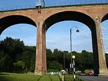 A large railway viaduct made from red bricks, topped by railings and electric pylons