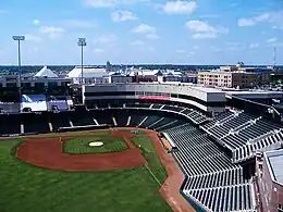 A green baseball field surrounded by a concrete concourse and green plastic seats