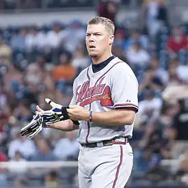 Chipper Jones, wearing an Atlanta Braves uniform, taking off his batting gloves