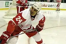 An ice hockey player on the ice. He is wearing a red and white jersey and white helmet.