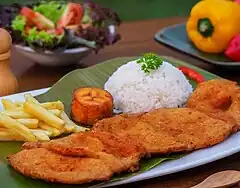 Image 7Cutlet "Valluna", a typical dish of the Valle del Cauca region of Colombia and the Afro-Colombian culture of the area near the Pacífic Ocean. It includes a milanesa, usually prepared with a lean pork loin beef or chicken can also be used. Traditional accompaniments include rice, sliced tomatoes, onions, chopped fried plantains or fries and a drink called "Lulada" made with lulo fruit, water and sugar (from Culture of Colombia)