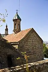 The view of the church from the inner garden. Over the pass, cut in the rock, Bolnisi Cross can be seen..