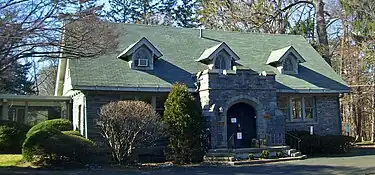 A stone building with a gabled roof, dormer windows and a castle-like front entrance