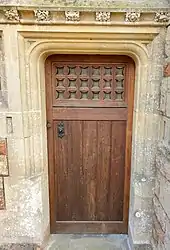 Colour photograph of the oak doorway with two trefoil‑cusped side windows that is surrounded by a paterae frieze.