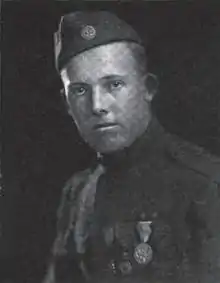 Head and shoulders of a young man in a military uniform with an array of medals on his chest and a garrison cap with a "US" button.