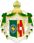 Coat of arms consisting of a shield with a green field with a golden armillary sphere over the red and white Cross of the Order of Christ, surrounded by a blue band with 20 silver stars; the bearers are two arms of a wreath, with a coffee branch on the left and a flowering tobacco branch on the right; and above the shield is an arched golden and jeweled crown