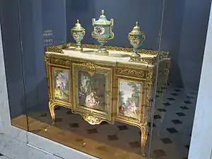 Louis XVI style commode of Madame du Barry; 1772; oak frame, veneer of pearwood, rosewood and kingwood, soft-paste Sèvres porcelain, gilded bronze, white marble, and glass; height: 0.87 m, width: 1.19 m, depth: 0.48 m