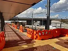 Train station platform with construction barriers on the platform and machinery on tracks