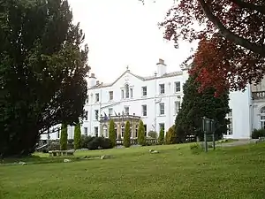 a large white house view across a lawn with trees