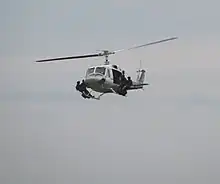 A helicopter flying with four special police troops standing on its landing skids