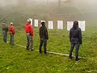 A line of people in front of targets with guns in holsters.