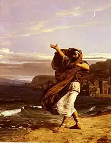  Man in robes with long brown hair against a background of waves reaching the shore