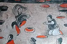 A male dancer wearing a black jiaolingpao over a pair of red trousers, Dahuting tomb, Eastern Han dynasty