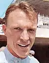 Dan Gurney in racing overalls smiling at the camera