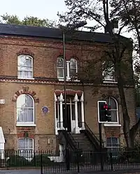 exterior of red bricked house, with blue plaque on front wall