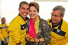 Two men wearing yellow outfits standing next to a woman with medals around her neck.