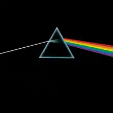 A prism refracting white light into a rainbow on a black background