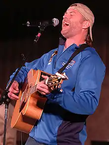 Singer Darryl Worley singing into a microphone while strumming an acoustic guitar