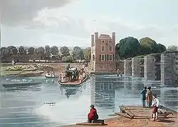 People cross a river using a small wooden boat. To the right the remains of four grey stone bridge supports with vegetation growing from the tops stand in the river