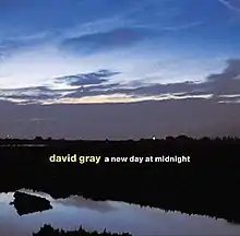 A photograph of a sunrise over a body of water with the artist and album title overlaid