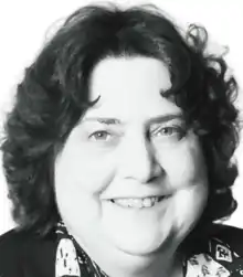 A black and white headshot of a smiling older woman with short hair.