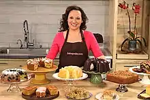 Woman standing behind a display of cakes