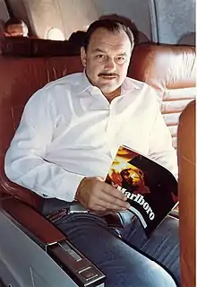 Dick Butkus reading a magazine in an airplane seat