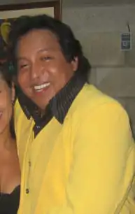 A man with a yellow sweater smiling.