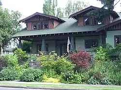 Photograph of a Craftsman bungalow with larger dormers, porch, and fieldstone steps.