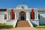 The design bears little resemblance to the local architecture of the time. The small elliptical gable on short pilasters is dated 1804. There is a straight gable at the back, obviously mid-19th century. The Drostdy has a large hall. The full depth of the Construction began in 1804 on the farm Rietvlei that had belonged to a Hercules du Pré.

The ex-landdrost, Bletterman of Stellenbosch, originally drew up plans for the Drostdy, but after some progress had been made, by order of landdrost Van de Graaff the design was changed to a plan by Louis- Michel Thibault. Much to the concern of Governor Janssens, the building took longer and cost more to be completed than had been anticipated, being finally finished in 1807. It is one of the few extant buildings at the Cape of which Thibault is the undisputed architect.

The Drostdy had already fallen into a state of disrepair by 1822, a reason put forward for making Worcester the seat of the drostdy instead of Tulbagh. The Drostdy was sold to a young settler named Heatlie, after which it remained a private dwelling with a small farm.

Towards the end of the century it again fell into disrepair, but was restored by Sir Meiring and Lady Beck. It burnt down in the mid-1930s, and was again restored. The 1969 Tulbagh earthquake caused further extensive damage. It was then acquired by the National Monuments Council and, during 1973, restored for the third time.

The building is now in use as offices, reception rooms and museum The outbuildings flanking the dwelling have been demolished; the one on the right since having been rebuilt. Type of site: Drostdy.