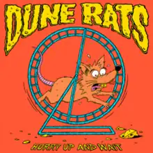 An orange rat running on a blue running wheel, looking at a small piece of cheese. The band's name is placed above in a cheese-like design and the album title is placed below in yellow.