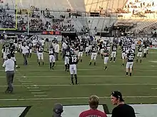 UCF football players, wearing black jerseys, going though warmups