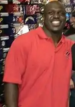 Color head-and-shoulders photograph of smiling African-American man (Earnest Graham) in coral-colored polo shirt.