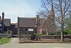 A stone building with a projecting bay, a tall chimney and a slim spire