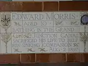 A tablet formed of five tiles of varying sizes, bordered by yellow and blue flowers in an art nouveau style