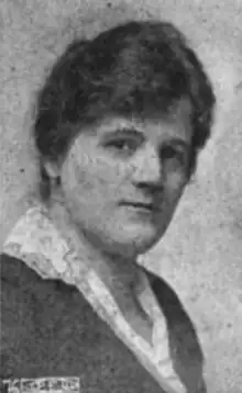 A black-and-white photograph of a white woman wearing a dark jacket with a lighter-color blouse with an open collar