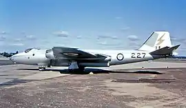 Side view of twin-jet, straight-winged aircraft parked on airfield