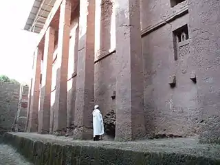 Man standing beside the walls of Biete Medhane Alem, believed to be the largest monolithic church in the world