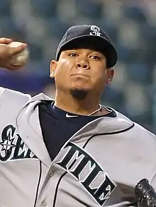 A man in a gray baseball jersey and navy blue cap