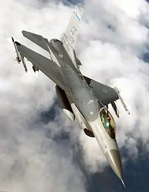 Upright aerial photo of gray jet aircraft flying above clouds