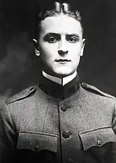 A picture of a hatless F. Scott Fitzgerald in his World War I military uniform taken in 1917. His tunic is fully bulleted, his golden hair is parted in the middle, and his white collar is starched.